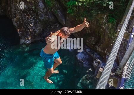 Mann springt von der Swing Bridge am Blue Pool in Wanaka, Neuseeland. Stockfoto