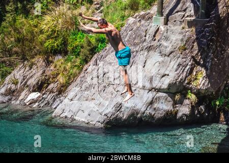 Mann springt von der Swing Bridge am Blue Pool in Wanaka, Neuseeland. Stockfoto