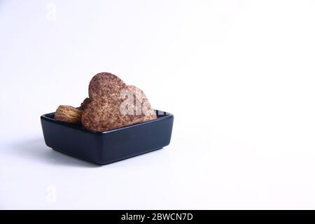 Herzförmige Plätzchen in schwarzer Schale auf weißem Hintergrund isoliert. Bild enthält Kopierbereich Stockfoto