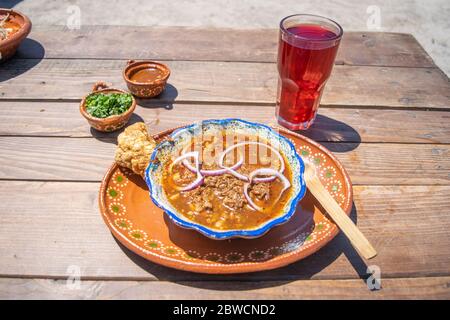 mexikanische Küche mit Birria, heißer Sauce und Chicharron, Koriander und frischem Wasser Stockfoto