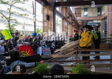 Demonstranten schreien, während Polizisten ruhig bei einem "Not Another Black Life"-Protest nach dem Tod von Regis Korchinski-Paquet in Toronto stehen. Stockfoto