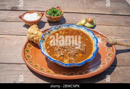 mexikanische Küche mit Birria, heißer Sauce und Chicharron mit und Avocados, Zwiebeln und Koriander Stockfoto