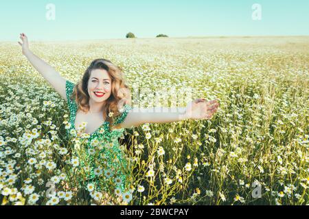 Frau mit offenen Armen in einem Feld von Gänseblümchen Stockfoto