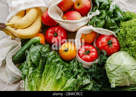 Frisches Gemüse und Obst in wiederverwendbaren Taschen aus Bio-Baumwolle auf dem Tisch in der Küche. Zero Waste Shopping Konzept. Nachhaltiges Leben Stockfoto