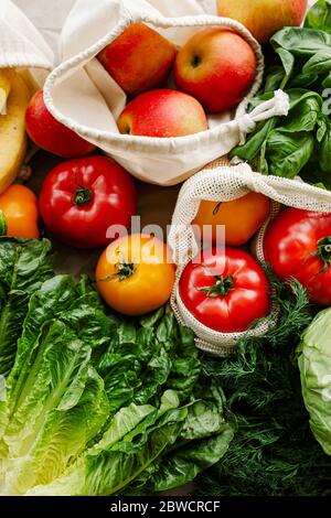 Frisches Gemüse und Obst in wiederverwendbaren Taschen aus Bio-Baumwolle auf dem Tisch in der Küche. Zero Waste Shopping Konzept. Nachhaltiges Leben Stockfoto