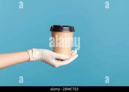 Profil Seitenansicht Nahaufnahme der menschlichen Hand in weißen chirurgischen Handschuhen halten und zeigen Tasse heißen Take away Becher Getränk in der Hand. Indoor, Studio-Aufnahme, isola Stockfoto