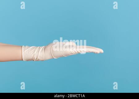Profil Seitenansicht Nahaufnahme der menschlichen Hand in weißen chirurgischen Handschuhen zeigt die Hand. Indoor, Studio-Aufnahme, isoliert auf blauem Hintergrund. Stockfoto
