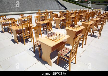 Gelbes und braunes Foto mit einem Bild von Schachbrettstücken, Holzstücken auf einem Schachbrett und Emtytisch . So spielen Sie Holzschach. Schach Stockfoto