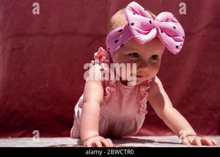 Nettes Baby Mädchen tragen liebenswert Hut tun Push-up im Freien, Blick auf die Kamera und lächelnd auf rotem Hintergrund Stockfoto