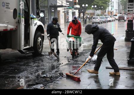 Seattle, WA, USA. Mai 2020. Menschen räumen Trümmer aus einem Auto auf, das in der Nacht zuvor während eines Aufruhrs am 31. Mai 2020 in Seattle, Washington, in Brand gesteckt worden war. Landesweit brachen Proteste über den Tod von George Floyd aus, der in der Obhut eines Polizisten starb, der sich in Minneapolis auf den Hals kniete. Kredit: Karen Ducey/ZUMA Wire/Alamy Live News Stockfoto