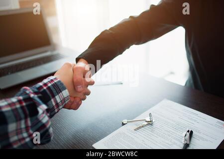 Immobilienmakler, der nach Vertragsunterzeichnung die Hände mit dem Kunden schüttelt Stockfoto