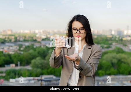 Die junge Frau hält vor dem Hintergrund der Stadt einen Desinfektionsmittel in den Händen Stockfoto