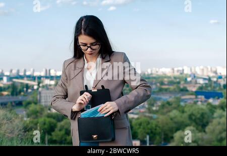 Medizinische Maske in einer Frauentasche, eine Handtasche mit Schutzausrüstung, in weiblichen Händen Nahaufnahme Stockfoto