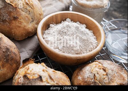 Holzschale aus Vollkornmehl in der Mitte von frisch gebackenen Sauerteig Brotschnecken. Stockfoto