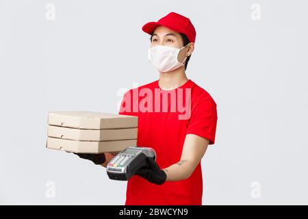 Kontaktlose Lieferung, sicherer Einkauf und Einkauf während des Coronavirus-Konzepts. Freundlicher Kurier in roter Uniform Mütze und T-Shirt, geben Kunden Pizza Stockfoto