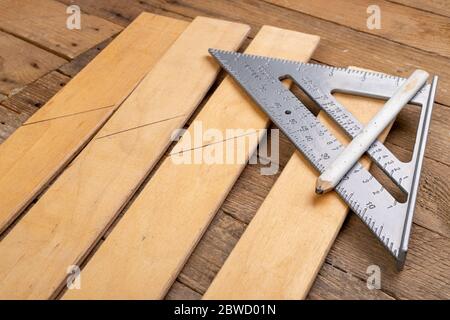 Zeichnen einer Linie in einer Schreinerei mit einem Winkelstab. Kleine Zimmerei in der Werkstatt. Heller Hintergrund. Stockfoto