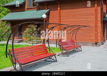 Bänke zum Entspannen in der Nähe eines Blockhauses an sonnigen Frühlingstag Stockfoto