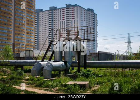 Rohre mit großem Durchmesser mit heißem und kaltem Wasser über dem Boden in der Nähe von Wohngebäuden im Sommer bei sonnigem Wetter installiert Stockfoto