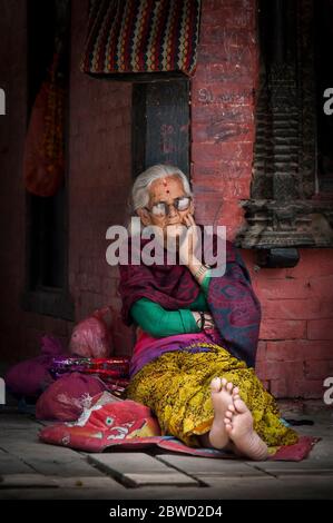 Unbekannte Newari ältere Frau sitzen vor dem Mul Chowk Königspalast in Patan Durbar Square - Lalitpur, Patan - Nepal Stockfoto