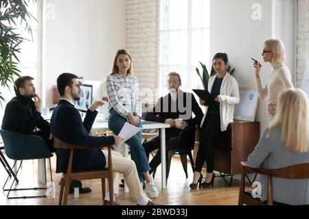 Multirassische Geschäftsleute hören selbstbewusste junge Sprecherin. Stockfoto