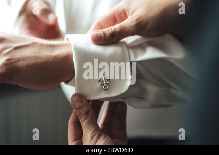 Bester Mann hilft Bräutigam zu kleiden. Herren Hände verstellende Hemdärmel mit Anker Manschettenknöpfe. Stockfoto