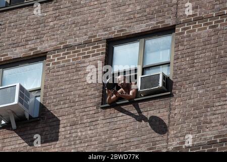 Ein Mann in einem Fenster, der mit einer Pfanne Lärm macht, um seine Unterstützung für den vorbeiziehenden marsch zu zeigen, der gegen die Ermordung von George Floyd durch die Polizei protestiert. Stockfoto