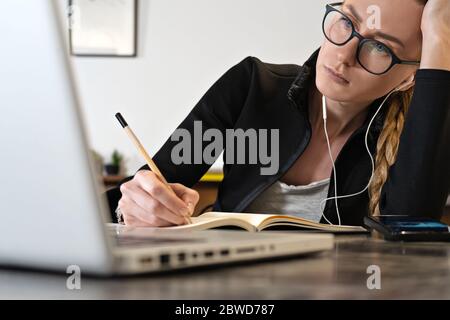 Müde Geschäftsfrau online arbeiten oder Ausbildung mit Laptop Notizblock studieren, Remote Working. Online-Lehrer oder Coach Stockfoto