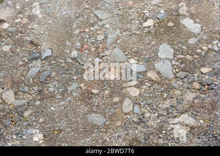 Steiniger Kies & Hardcore-Land Schotterpiste. Metapher für "Fall auf steinigen Boden", schlechte Qualität, raue Straßenkonzept, kleine Steine, zufällig, felsige Straße. Stockfoto