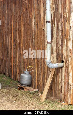 Einfache Installation von Gasbehälter außerhalb bescheidenen Holz und Kamin für Rauchabgang. Stockfoto