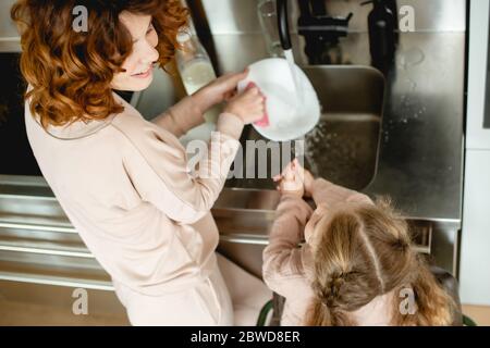 Overhead-Ansicht von glücklichen Kind Waschplatte mit fröhlichen Mutter Stockfoto