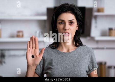 Verärgerte Frau mit Blutergüssen im Gesicht und schwarzem Punkt auf der Handfläche, häusliche Gewalt Konzept Stockfoto