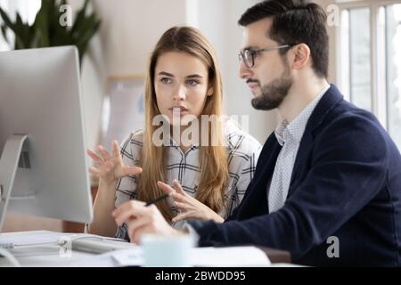 Fokussierte junge weibliche Mitarbeiterin erklärt Forschungsergebnisse zu männlichen Chef. Stockfoto