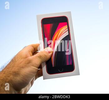 Paris, Frankreich - 19. Mai 2020: Mann Hand POV hält vor blauem Himmel Hintergrund neue Apple Computers iPhone SE 2020 Version Produkt Rote Version Stockfoto