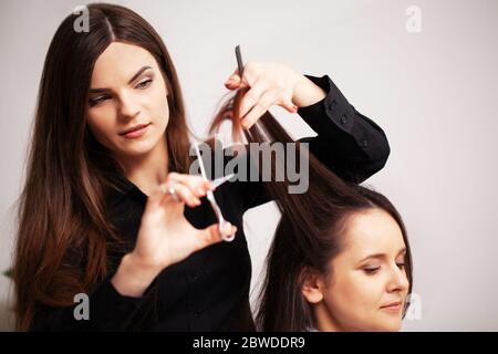 Professionelle Stylistin macht eine junge Frau eine schöne Frisur Stockfoto