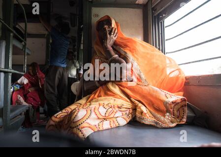 Frau mit Blick aus fahrenden Zug Fenster, zweite Klasse Zug. Indian Railways. Indien. Stockfoto