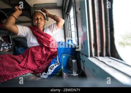 Frau mit Blick aus fahrenden Zug Fenster, zweite Klasse Zug. Indian Railways. Indien. Stockfoto