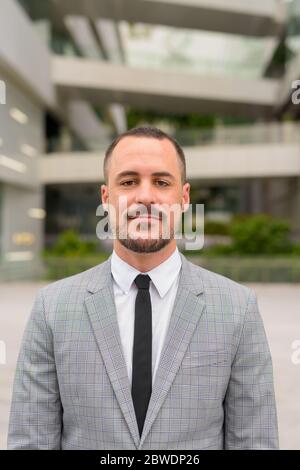 Gesicht von gutaussehenden hispanischen kahlen bärtigen Geschäftsmann in der Stadt im Freien Stockfoto