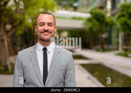Schöner hispanischer kahlbärtiger Geschäftsmann mit Natur in der Stadt im Freien Stockfoto