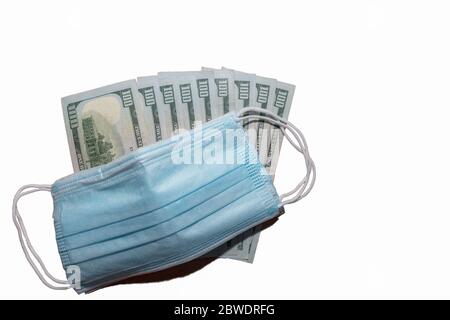 Gesichtsschutz chirurgische Masken auf ein paar hundert Dollar Rechnungen. Isoliert. Weißer Hintergrund. Teurer Schutz vor Viren und Bakterien. Stockfoto