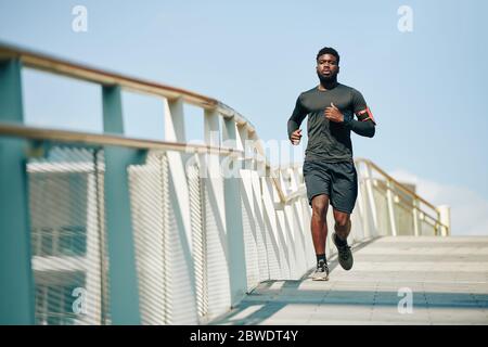 Fit schönen jungen schwarzen Sportler Joggen auf Brücke am Morgen Stockfoto