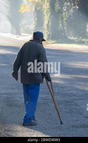 Alberton, Südafrika - nicht identifizierter körperlich behinderter älterer Mann geht auf der Straße mit einem Krücken-Bild im vertikalen Format Stockfoto