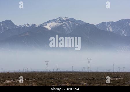 Hochspannungs-Pylonen auf trockenem Grasland im Morgennebel Stockfoto