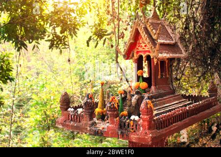 Traditionelles Geisterhaus im tropischen Dschungel, Laos. Kleiner Altar für Geister in Form eines Miniaturtempels, zu dem tägliche Opfergaben gebracht werden Stockfoto