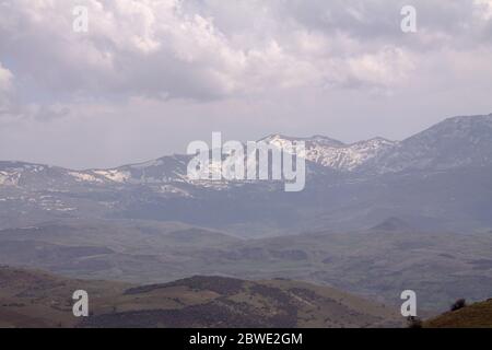 Blick über die Hügel mit Mountain Trail und schneebedeckten Bergen im Hintergrund. Schöne Mountain Trail Landschaft. Morgen Alborz Mountain Trail Szene Stockfoto