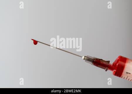 Spritze mit einer Blutprobe. Ein Tropfen Blut am Ende der Nadel. Blutchemie. Bluttest auf Viren. Stockfoto