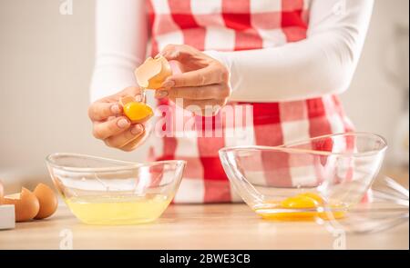 Detail der Hände der Frau, die Eigelb vom Weißen in zwei Glasschüsseln trennt Stockfoto