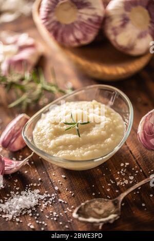 Knoblauchpaste in einer Glasschüssel mit geschältem Knoblauch, Salz und Knoblauchköpfen Stockfoto