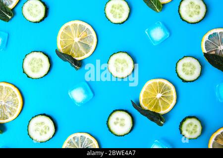 Zutaten zum Kochen kalten Frühling Limonade Getränk mit Gurke, Zitronenstücke, frische Blätter Minze Eiswürfel auf blauem Hintergrund, Draufsicht Stockfoto