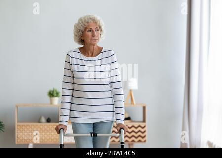 Ältere Frau im Wohnzimmer stehend mit Gehgestell Stockfoto