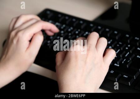Weibliche Hände auf Computer-Tastatur Nahaufnahme, selektive Fokussierung. Frau drückt die Tasten, Konzept des Büros oder der Heimarbeit Stockfoto